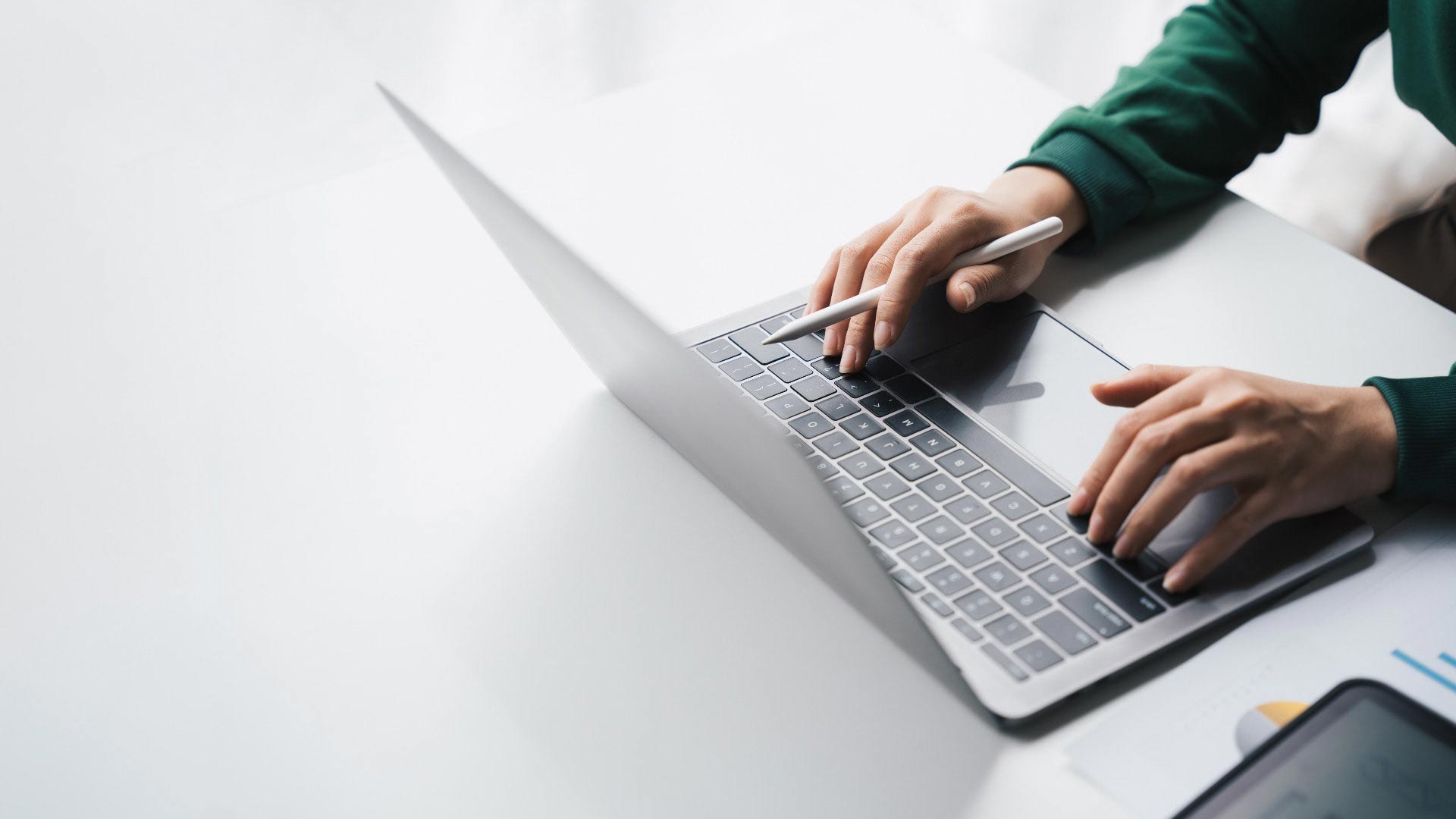 Ein Mensch arbeitet am Laptop und hat einen Stift in der Hand